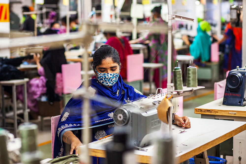 Una trabajadora de la industria textil realiza su trabajo mientras mantiene distancia social con otros trabajadores/as, a medida que las fábricas de confección de ropa reinician actividades después de la epidemia de COVID-19 en Dhaka. Fotografía: UN Women/Fahad Abdullah Kaizer